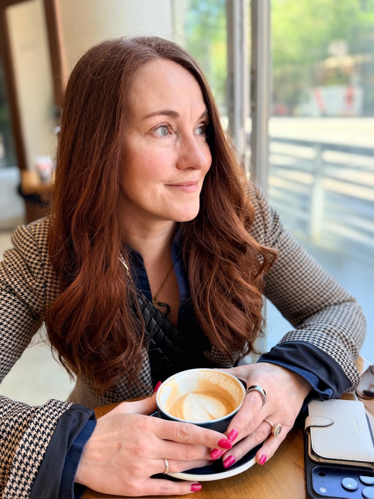 Clare, founder of Wend, holding a coffee in a sunlit café.